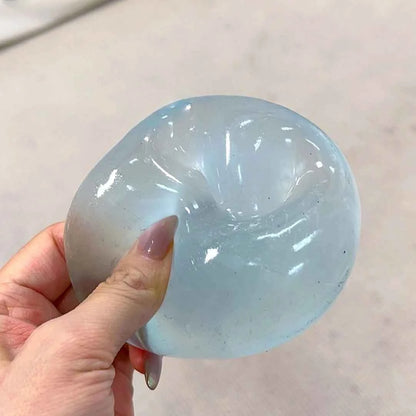 Chiboki coconut oil squishy, translucent blue, held in hand with a dent from squeezing